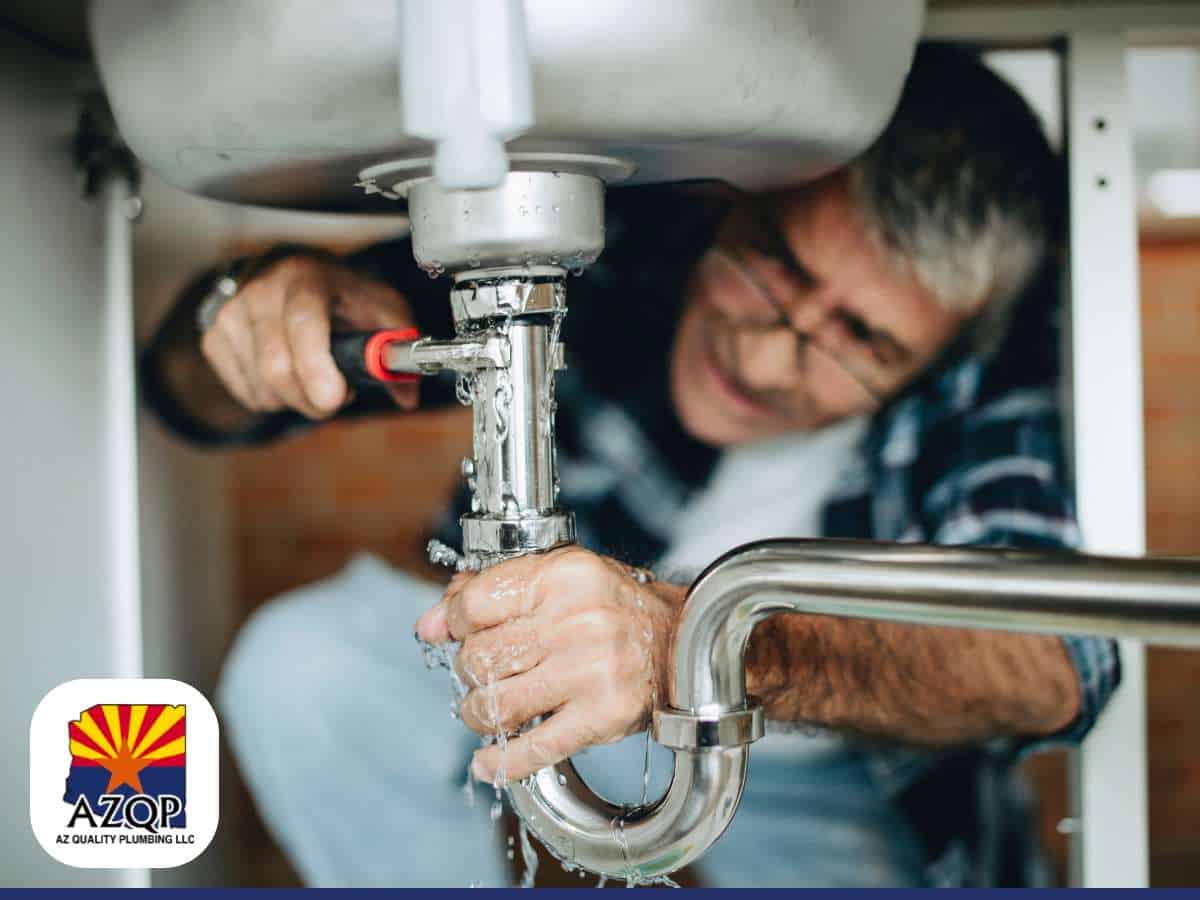 Fixing a kitchen sink leak with plumbing tools under the sink